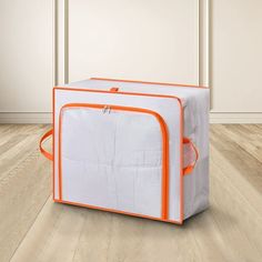 an orange and white cooler sitting on top of a hard wood floor next to a wall