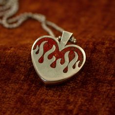 The silver hearts on fire pendant features a chunky design and a stunning ruby red opal inlay (or your chosen stone). Alternatively, you can opt for a transparent pendant without any inlay. It boasts a substantial 4 mm thickness and stands 26 mm tall. PLEASE READ: The production and delivery of your piece may take anywhere from 2-4 weeks as it is custom made by a real person. Grit Trade Co. is a curated collection of unique sterling silver jewelry inspired by American culture, music, and motorcy Unique Red Heart Shaped Jewelry, Red Sterling Silver Heart Pendant Jewelry, Red Heart-shaped Engraved Jewelry, Red Engraved Heart-shaped Jewelry, Red Polished Jewelry For Valentine's Day, Red Sterling Silver Jewelry With Polished Finish, Collectible 925 Stamped Heart Pendant Jewelry, Collectible Stamped 925 Heart Pendant Jewelry, Red Sterling Silver Jewelry With Inlay