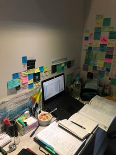 a laptop computer sitting on top of a desk next to a bowl of food and notebooks