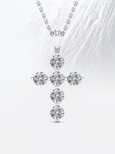 a diamond cross pendant with feathers in the background