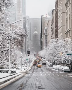 a city street is covered in snow and cars are parked on the side of the road