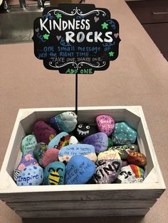 a box filled with lots of rocks sitting on top of a table next to a sign