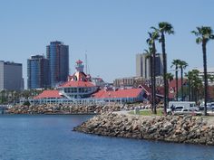 there is a red and white building next to the water with palm trees in front of it