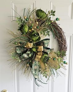 a wreath with green and gold decorations hanging on a door