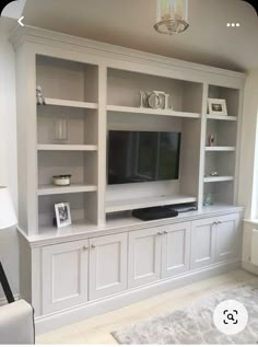 a living room with white bookcases and a flat screen tv