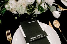 a place setting with white flowers and black napkins