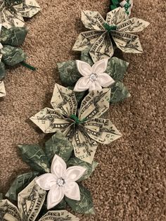 dollar bills and white flowers are arranged on the floor with green ribbons around them, as if they were made out of money