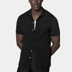 A perfect way to elevate any casual look, this black short-sleeve polo cardigan features a classic polo collar, a seven-button closure, and a slim, tapered silhouette for a sleek aesthetic. Modern Short Sleeve Cotton Polo Sweater, Modern Cotton Short Sleeve Polo Sweater, Short Sleeve Workwear Polo Sweater With Ribbed Collar, Short Sleeve Polo Sweater With Ribbed Collar For Workwear, Workwear Polo Sweater With Short Sleeves And Ribbed Collar, Business Casual Short Sleeve Polo Shirt With Ribbed Collar, Classic Black Polo Sweater With Button Closure, Short Sleeve Polo Sweater For Summer Workwear, Summer Short Sleeve Polo Sweater For Work