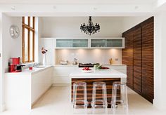 a kitchen with white cabinets and counter tops next to a chandelier hanging from the ceiling