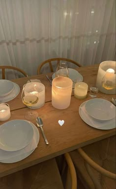 a wooden table topped with white plates and glasses