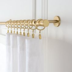 the curtain rod is hanging on the wall next to the white drapes with gold hardware