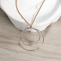 Elevate your style with this bold, mixed metal necklace designed for powerful, fashion-forward women. This unique piece features an original Lepa Jewelry design with two extra-large, open-frame Argentium Sterling Silver circles, one nested inside the other and artfully shaped into waves. These striking circles hang from a figure-8 gold-filled chain, giving the necklace an elegant mixed metal finish. The chain measures 18", and the pendant adds up to an overall length of approximately 21", making it a statement piece perfect for career-oriented women who wear jewelry to feel empowered and chic. Crafted from high-quality, heavy-gauge metals, this necklace stands out from average circle necklaces with its thoughtful design and superior craftsmanship. Whether it's a gift for a special occasion Everyday Silver Brass Chain Necklace, Modern Hammered Round Necklace, Modern Silver Brass Necklace, Silver Circle Brass Necklaces, Everyday Metal Necklace With Polished Finish, Gold Sterling Silver Chain Necklace Nickel Free, White Gold Brass Necklace With Round Pendant, Hand Forged Round Metal Necklace, Gold Circular Necklace With Polished Finish