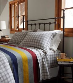 a bed with plaid sheets and pillows in a bedroom