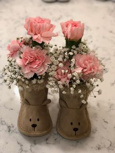 two brown boots with pink flowers in them on a marble countertop next to white baby's breathflowers