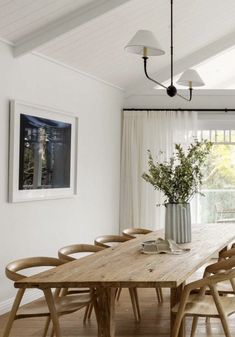 a dining room table with chairs and a vase filled with flowers on top of it