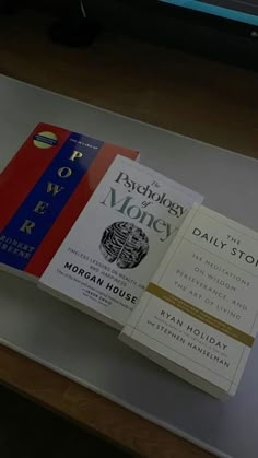 two books are sitting on top of a glass table in front of a computer monitor