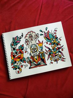 a notebook with an image of a skeleton and flowers on the cover is sitting on a red sheet