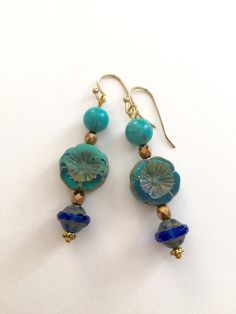 "Lightweight earrings handmade of semi-transparent aqua blue Czech glass Picasso flower, 8mm turquoise howlite, and cobalt blue Picasso UFO bead. Accented with light bronze Czech glass beads and gold wire. Earrings come on simple gold plated fish hook ear wires, lead and nickel free. Measure 2 1/8\"'long from top of ear wire." Artisan Blue Beaded Round Earrings, Artisan Blue Beaded Earrings As Gift, Blue Round Beaded Earrings With Spacer Beads, Turquoise Glass Earrings For Gift, Artisan Blue Nickel-free Earrings, Artisan Blue Beaded Earrings, Handmade Blue Round Bead Earrings, Nickel-free Turquoise Czech Glass Jewelry, Artisan Blue Round Beaded Earrings