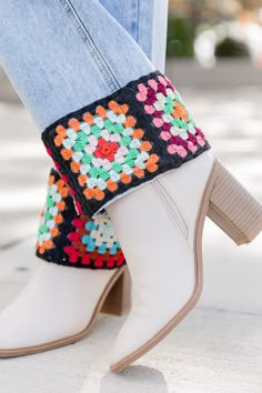 a woman wearing white boots with colorful crochet on them