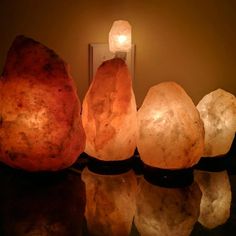 three large rocks sitting on top of a table next to a lit candle and mirror