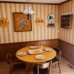 a dinning room table with plates on it in front of a wallpapered wall