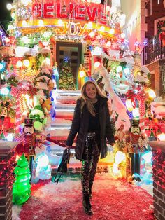 a woman standing in front of a building covered in christmas lights and decorations at night