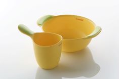 two yellow bowls with spoons sitting next to each other on a white table top