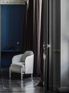 a white chair sitting in front of a window next to a blue wall and floor