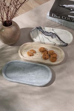 three plates with cookies on them sitting on a table next to a book and vase