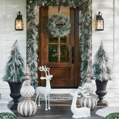 christmas decorations on the front porch with deer and pineconi trees in pots next to it