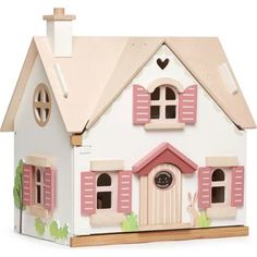 a doll house with pink shutters and windows on the front, sitting on a white surface