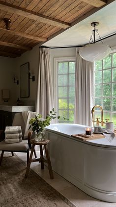 a bathroom with a large tub next to a window and a table in front of it