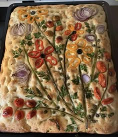 a square pizza with various toppings on it sitting on top of a stovetop