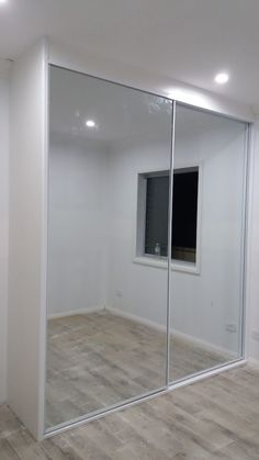 an empty room with a large mirror on the wall and wood flooring in front of it