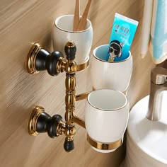 there are cups and toothbrushes in the holder on the bathroom wall next to the faucet