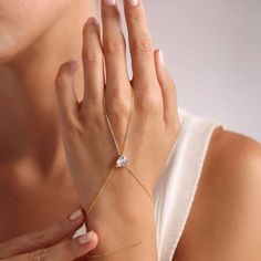 This beautiful hand chain is crafted from sterling silver and features a dainty chain. The centerpiece of the chain showcases a stunning heart-shaped zircon gemstone, exuding a casual yet sophisticated vibe. Show off your romantic side (without being cheesy) with this delicate design. Metal: 925 sterling silver Finish: 18k gold Gemstone: white zirconia Bracelet length: adjustable with 4 cm extender (1.5") Chain: cable link Clasp: spring ring Hypoallergenic, nickel-free Don’t forget, proper care Heart-shaped Chain Jewelry For Weddings, Luxury Cubic Zirconia Heart Bracelet, Minimalist Heart Cut Cubic Zirconia Jewelry, Delicate Diamond White Jewelry For Promise, Delicate Diamond White Promise Jewelry, Cubic Zirconia Gemstone Jewelry For Promise, Cubic Zirconia Promise Jewelry With Gemstone, Dainty Cubic Zirconia Chain Bracelet For Parties, Adjustable Diamond White Jewelry For Promise