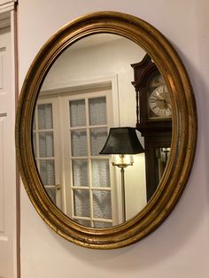 a large mirror hanging on the wall next to a lamp and door with a clock in it