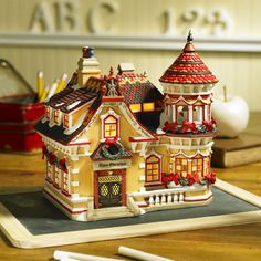 a small model of a house on top of a wooden table next to some markers