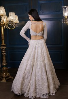 a woman in a white dress standing next to a chandelier