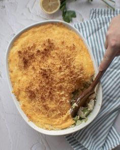 a person is holding a spoon in a casserole dish with bread crumbs