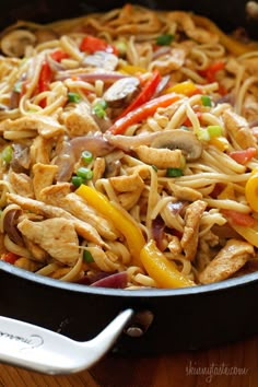 a skillet filled with chicken, peppers and noodles