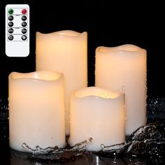 four lit candles sitting next to each other on top of a glass table with water around them