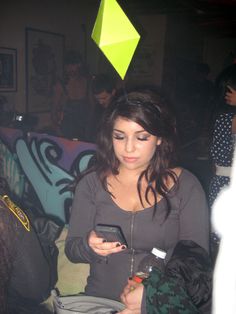 a woman is looking at her cell phone while standing in a room with graffiti on the walls