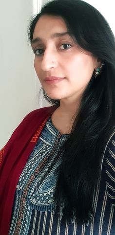 a woman with long black hair wearing a red shawl and looking at the camera