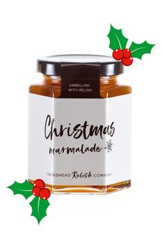 a jar of christmas marmalade with holly leaves and berries on the side, next to it's label