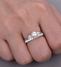 a woman's hand with a pearl and diamond ring