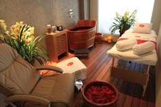 a spa room with two massage beds and flowers on the floor next to each other