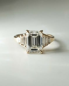 an emerald cut diamond ring with three baguets