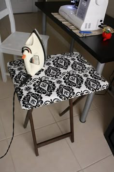 an ironing board sitting on top of a table next to a white and black chair