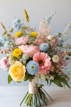 a bouquet of colorful flowers in a vase on a white table with blue and yellow accents